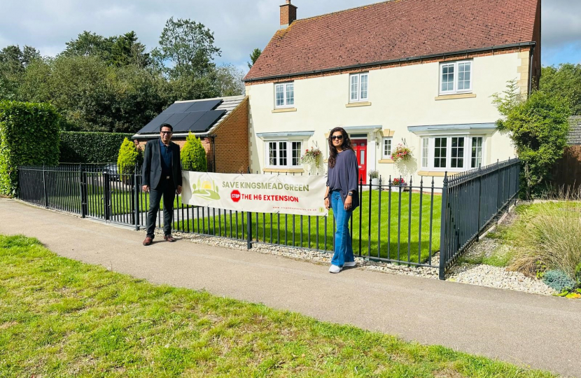 Cllrs Muzammil and Verma stand in front of campaign sign 