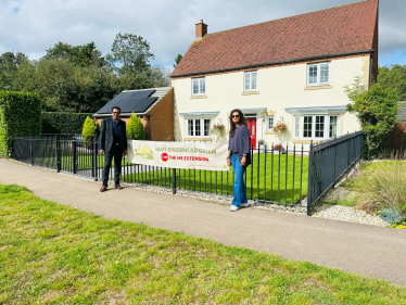 Cllrs Muzammil and Verma stand in front of campaign sign 